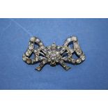 An early 19th century mine cut diamond set bow in unmarked metal mount, having later brooch fitting,