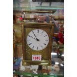 A large antique brass carriage clock, striking on a bell,