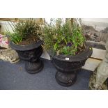 A pair of black painted composition stone twin handled urns, 66cm high.
