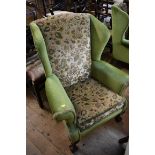 A pair of walnut and upholstered wing armchairs, on ball and claw feet to the front.