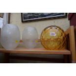 A set of three etched glass shades; together with another amber glass shade.