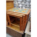 A nest of three teak tables, the largest with tile inset surface,