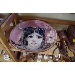 A pottery dish, painted with a lady, 32cm wide.