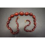 A knotted string of graduated cherry red amber style beads, 57cm, 48g.
