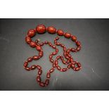 A string of graduated cherry red amber style beads, 113cm, 93.5g