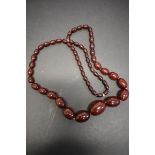 A string of graduated dark cherry amber style beads, 96cm, 114g.