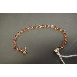 A 9ct gold heart facet cut orange sapphire tennis bracelet.