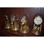 Four various anniversary clocks, each with glass dome.