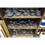 A collection of black basalt cream jugs, sugar bowls and bachelor's teapots. (3 shelves)