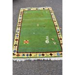 A Persian rug, having central green field with tree and figure design having border decorated with