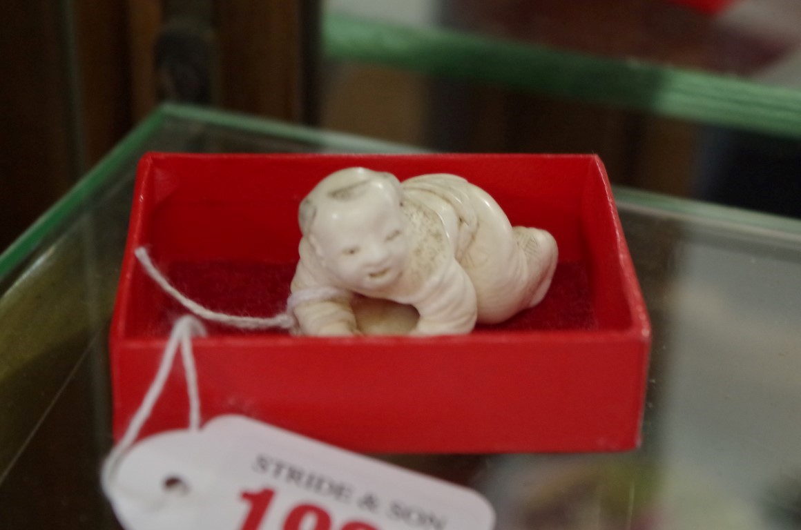 A Japanese carved ivory netsuke of a child with a fan, 3.7cm long.