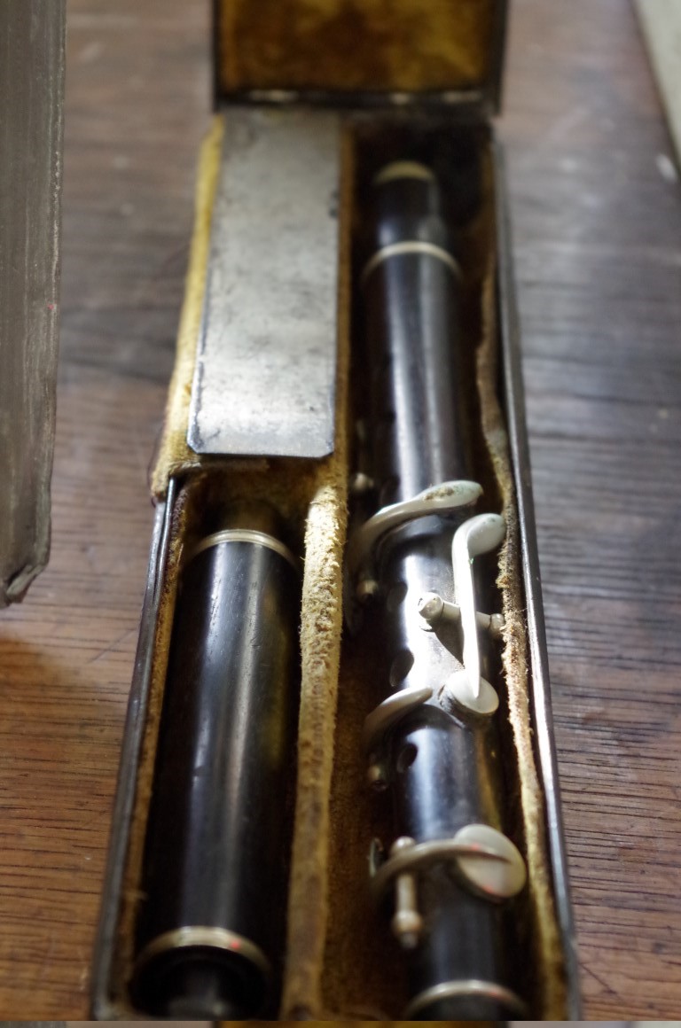An antique ebony flute, in metal tin. (please note this is a piccolo)