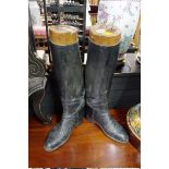 A pair of black leather boots and wooden trees.