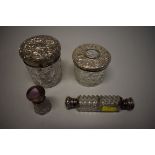 A double ended cut glass perfume bottle; together with three silver lidded cut glass jars.