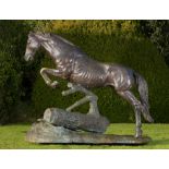 Equestrian/Garden Sculpture: A life size bronze group of a stallion jumping over a log