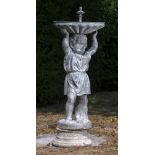 A lead birdbath in the form of a boy holding aloft a replaced dish, mid 20th century, on composition