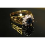 AN 18ct DIAMOND AND SAPPHIRE CLUSTER RING, having a single round cut sapphire surrounded by a row on