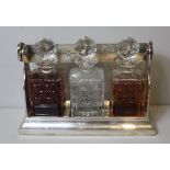 AN EARLY 20th SILVER PLATED AND CUT GLASS TANTALUS, of plain form with locking mechanism,