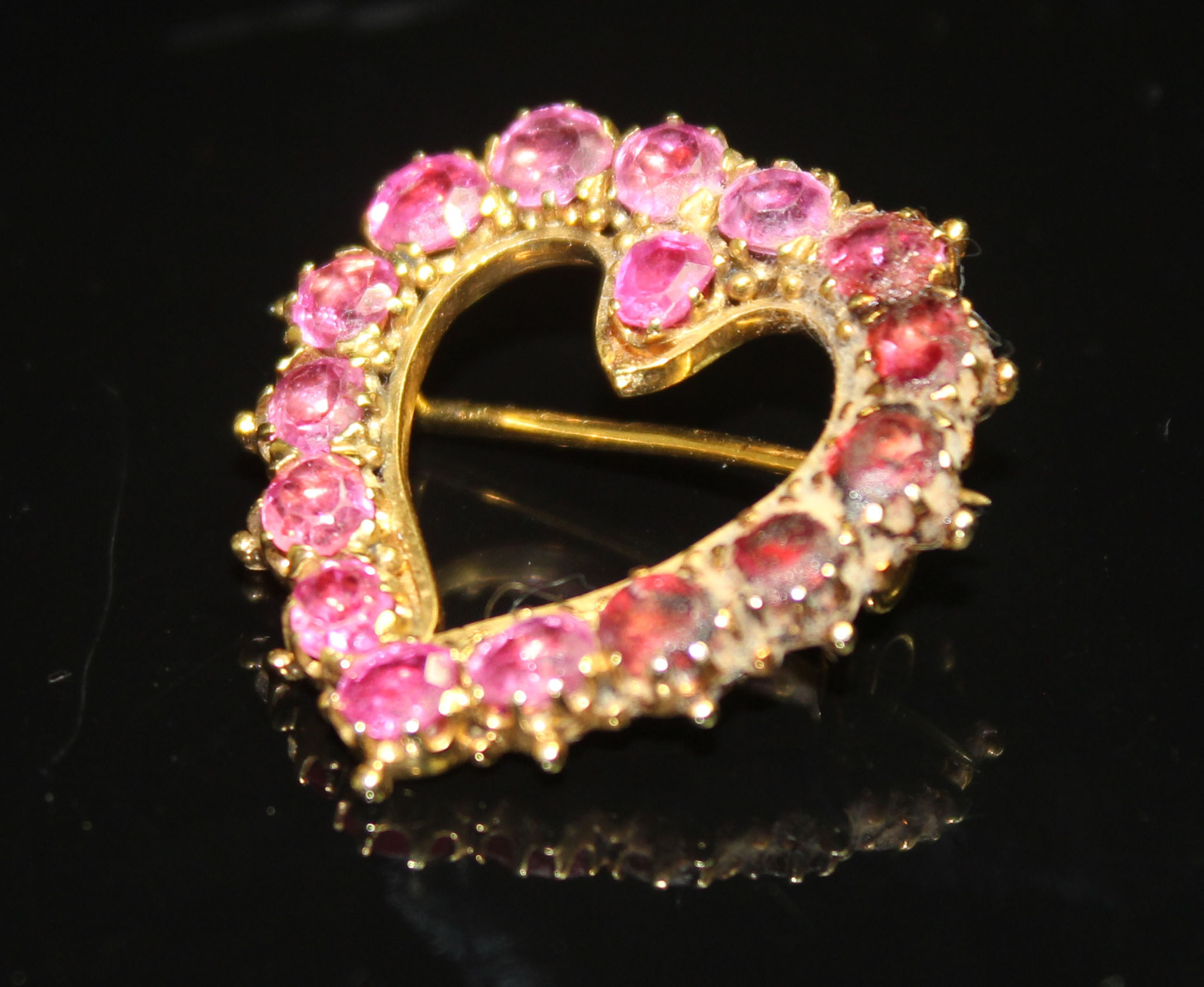 A 19TH CENTURY RUBY HEART BROOCH of yellow metal and open form. Set throughout with circular-cut