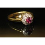 AN 18CT GOLD, DIAMOND AND RUBY CLUSTER RING Having a single round cut ruby flanked by a row of