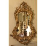AN EARLY 19TH CENTURY CARVED GILT WOOD MIRROR, of cartouche form 66 x 93 cm