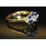 AN 18CT GOLD, DIAMOND AND SAPPHIRE DAISY CLUSTER RING Having an arrangement of six sapphires and