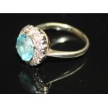 AN EARLY 20TH CENTURY TOPAZ AND DIAMOND CLUSTER RING, centred with a circular-cut blue topaz in a