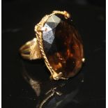 A VINTAGE SMOKY QUARTZ COCKTAIL RING. The large oval mixed-cut quartz in a four-claw setting