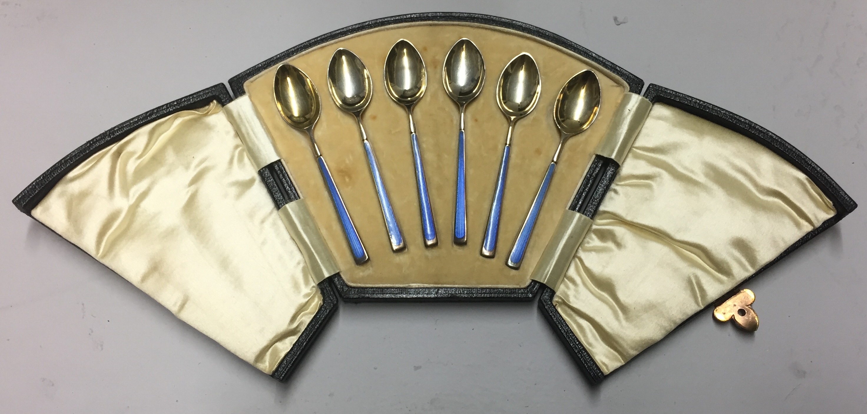 LEVI & SALAMAN, A SET OF SIX ART DECO SILVER GILT COFFEE SPOONS With blue guilloché enamelled