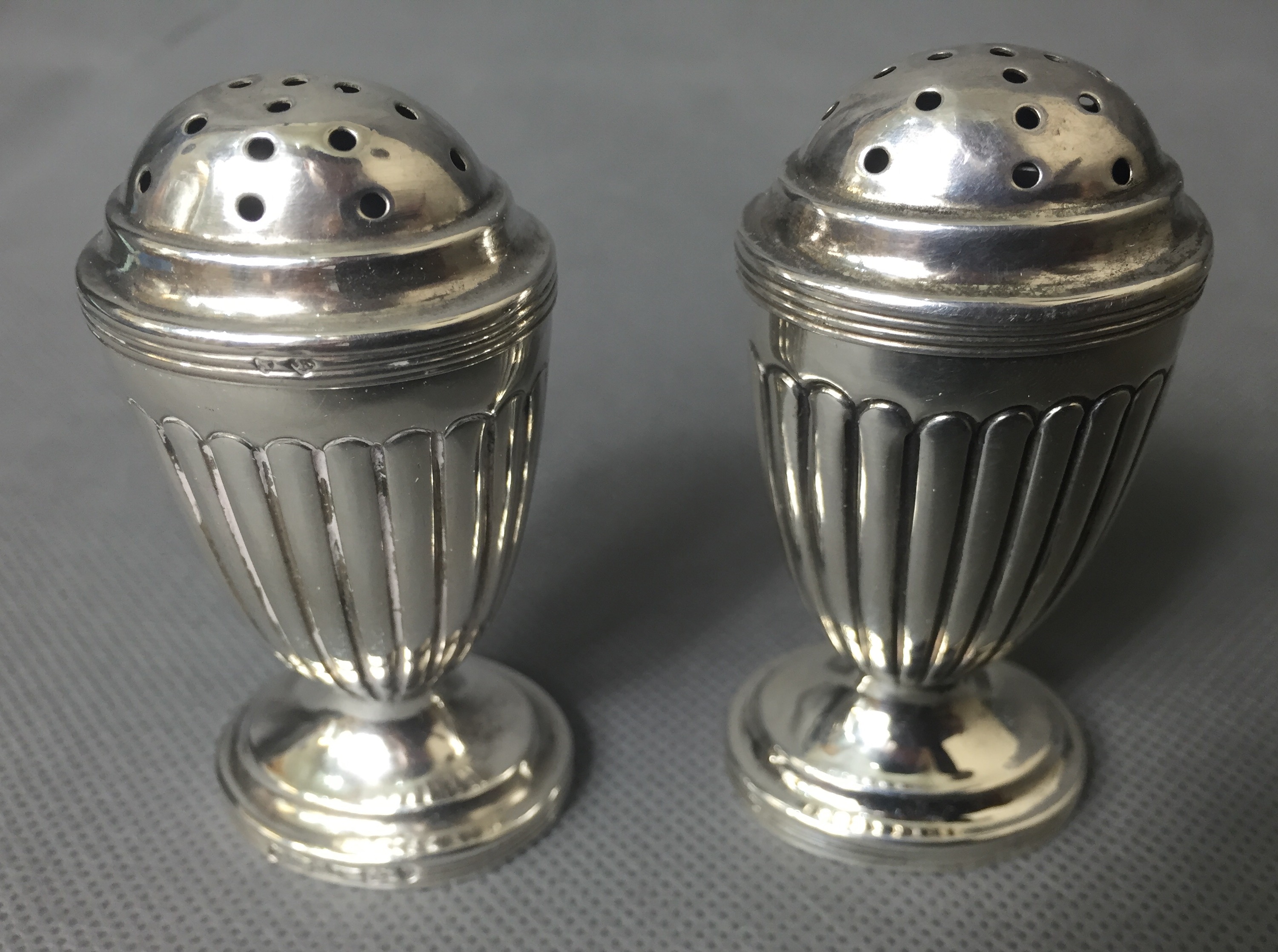 A PAIR OF VICTORIAN SILVER PEPPER POTS Of Neoclassical design with semi reeded body raised on