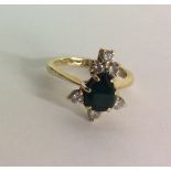 A VINTAGE EMERALD AND DIAMOND RING Having a pear shape emerald set with a cluster of round cut