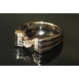 AN 18ct WHITE GOLD AND DIAMOND RING, having a single round cut diamond flanked by two rows of