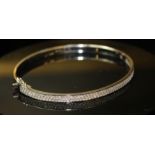 AN 18ct WHITE GOLD AND DIAMOND BANGLE, having a single band of pave set diamonds Approx 6.5cm in