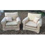 A PAIR OF EASY ARMCHAIRS Upholstered in a floral fabric on a cream ground, of generous per