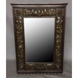 A LATE 19TH CENTURY OAK AND REPOUSSE BRASS FRAMED MIRROR, The bevelled plate surrounded by classical