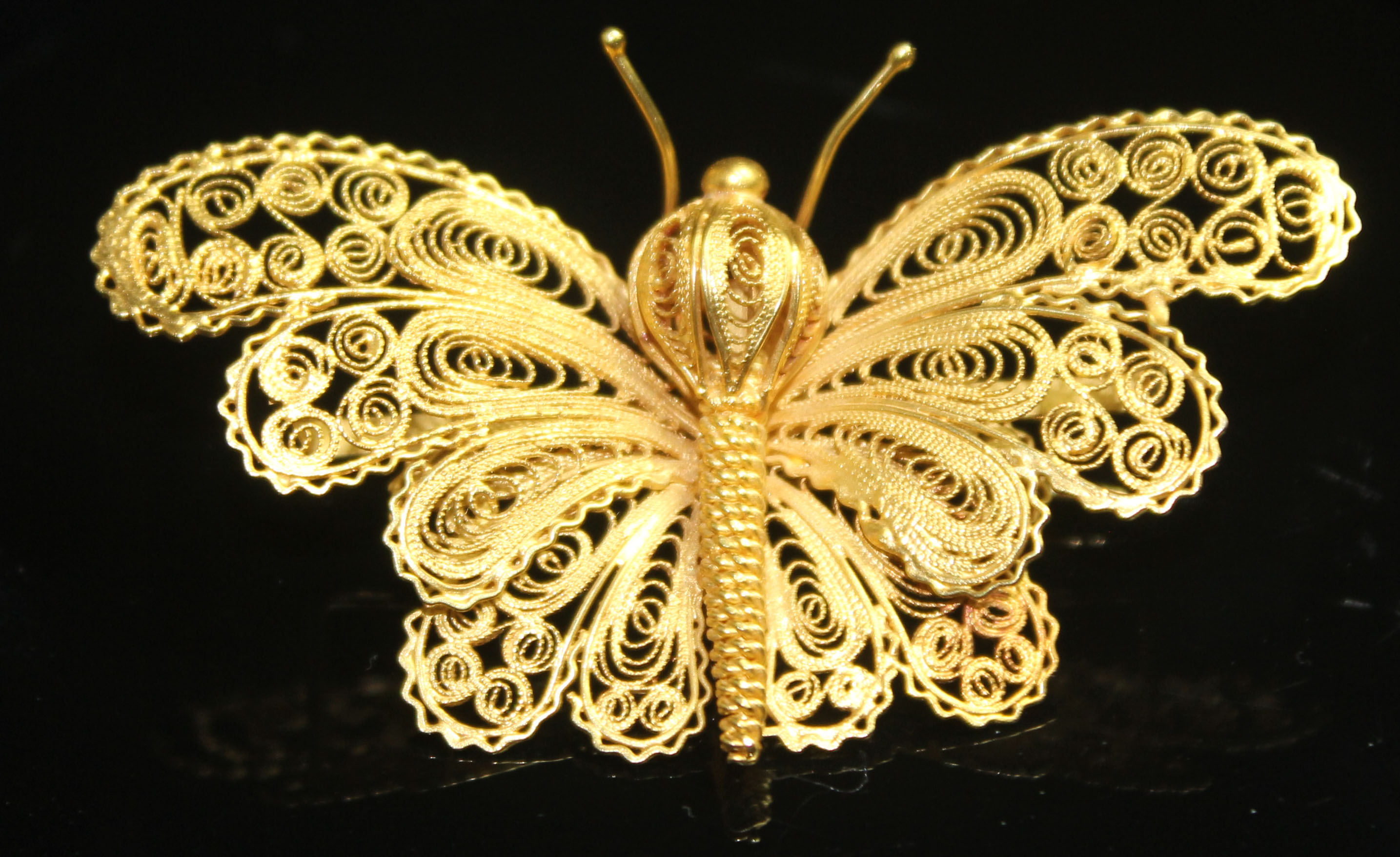 A YELLOW METAL FILIGREE BUTTERFLY BROOCH, with a ropetwist wirework body and scrolling wirework