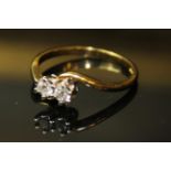 AN 18ct GOLD AND TWO STONE DIAMOND RING, having two round cut diamonds held in a cross over style