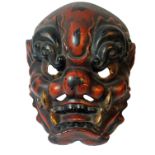 A 19TH CENTURY JAPANESE LACQUER DEMON MASK The fierce long-toothed creature lacquered in red,