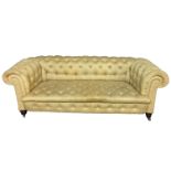 A VICTORIAN CHESTERFIELD THREE SEAT SETTEE In oatmeal button back fabric upholstery, raised on