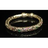 A MULTI-GEM SET ELEPHANT BANGLE, of hollow, intricately pierced and slightly tapering form with