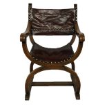 A 20TH CENTURY CARVED OAK AND STUDDED MAROON LEATHER X FRAME ARMCHAIR.