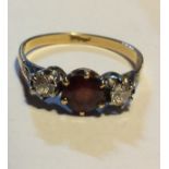 AN 18CT GOLD, DIAMOND AND GARNET THREE STONE RING Having a single round cut garnet flanked by two