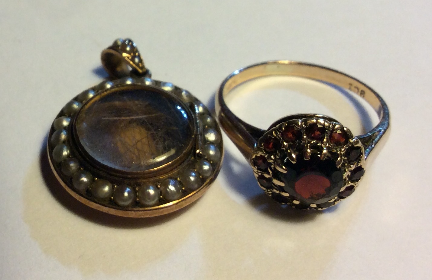 AN EDWARDIAN YELLOW METAL AND SEED PEARL MOURNING CIRCULAR LOCKET Set with a single row of seed