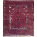 AN ANTIQUE AFGHAN WOOLLEN PRAYER RUG Red ground and woven with an arched design to centre field. (