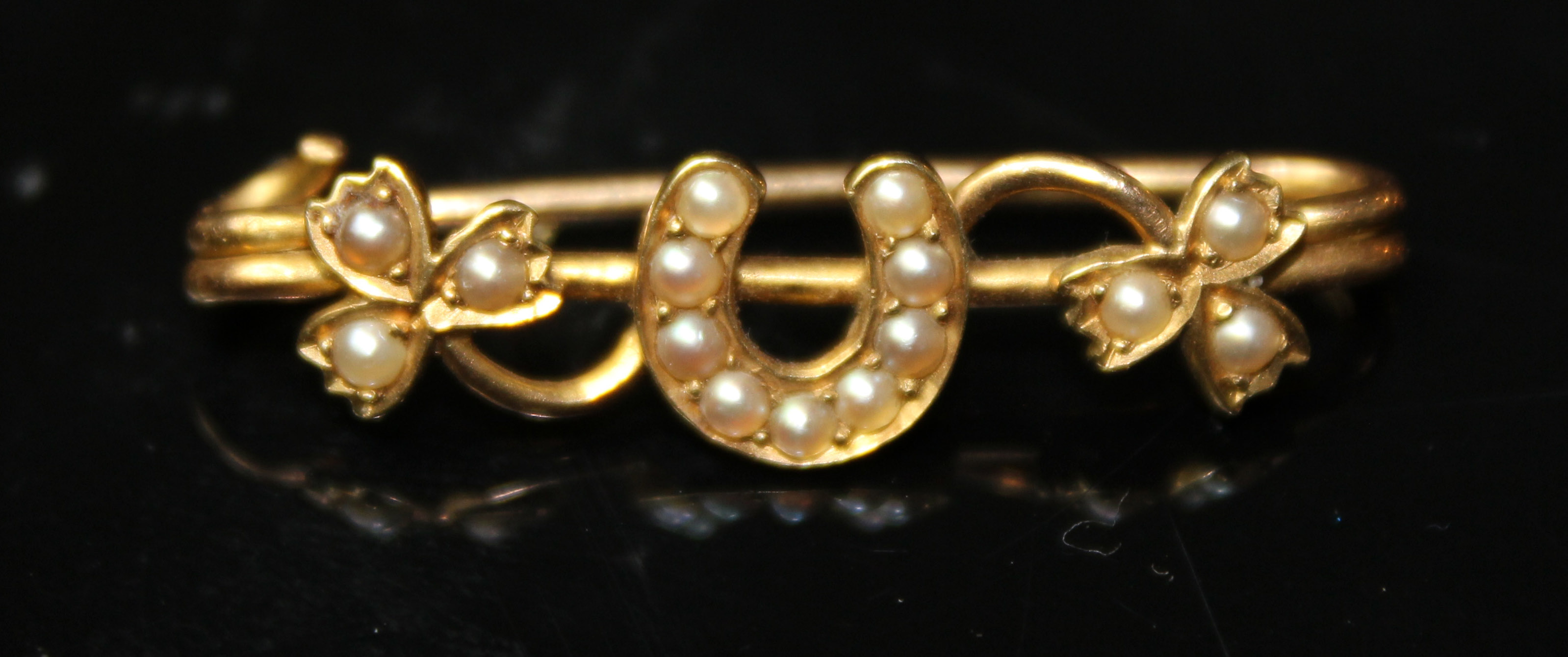 A VICTORIAN YELLOW METAL AND SEED PEARL BROOCH Having a lucky horseshoe and shamrock design. (approx