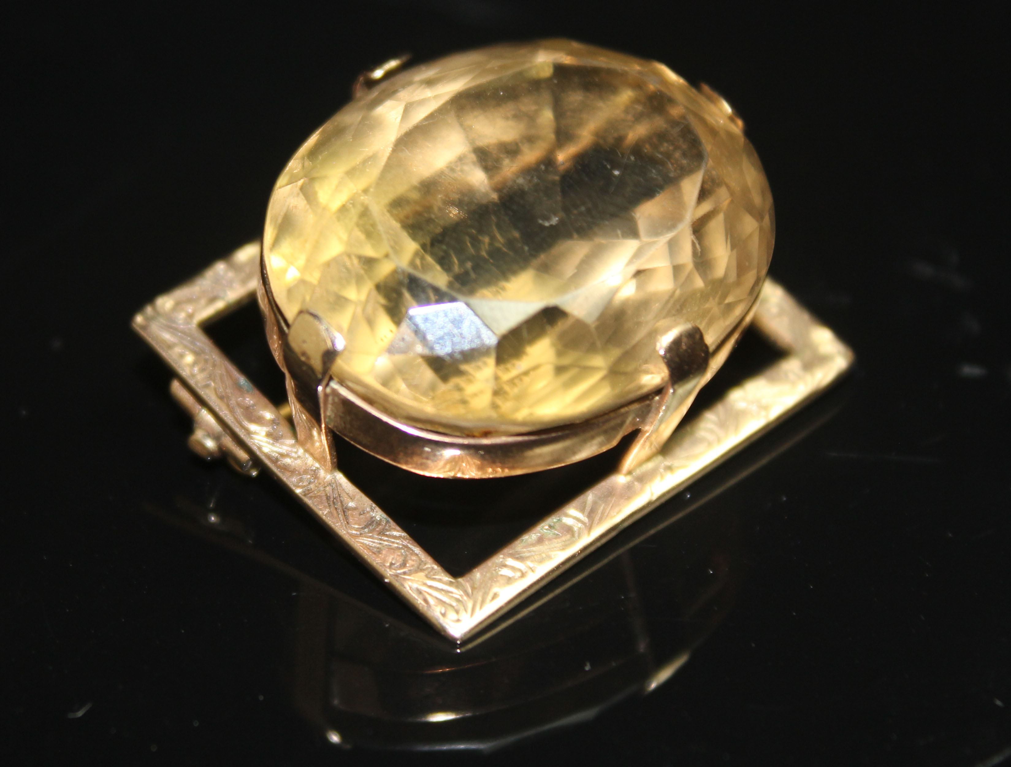 A LARGE VINTAGE CITRINE AND GOLD PANEL BROOCH The large oval mixed cut citrine in a high four claw