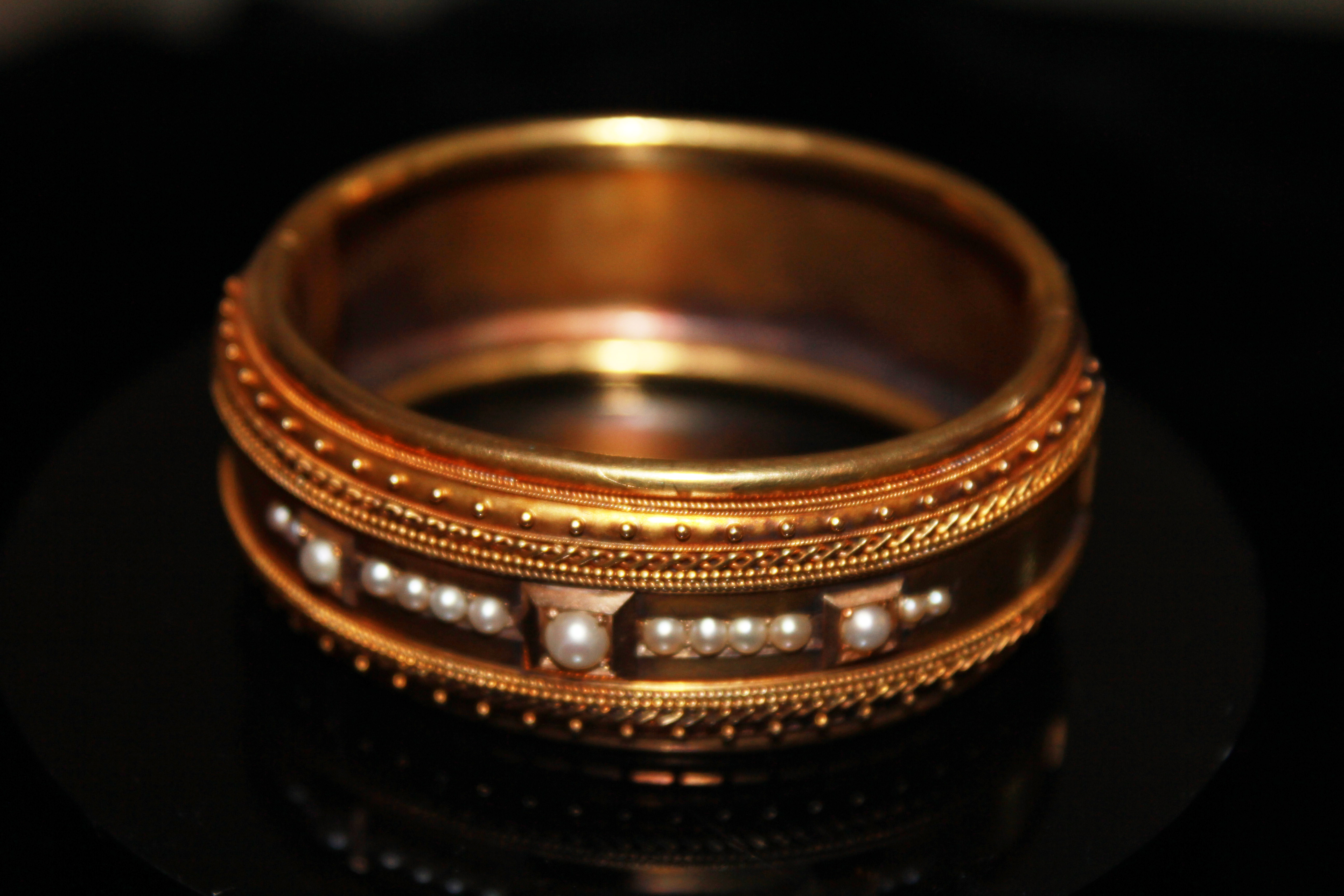 A VICTORIAN YELLOW METAL AND PEARL BANGLE Having three graduating pearls interspersed with seed