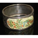 A 19TH CENTURY WHITE METAL AND ENAMEL HINGED BANGLE having a central panel of cream enamel hand