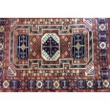 AN AFGHAN WOOLLEN RUG Terracotta field with three graduating lozenge panels woven to central