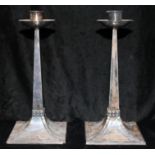 A PAIR OF EDWARDIAN ARTS & CRAFT STYLE SILVER CANDLESTICKS With circular drip pans tapering stem and